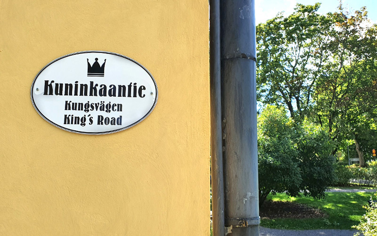 Entisajan Kuninkaantien kyltti reitin varrella olevan rakennuksen seinässä.